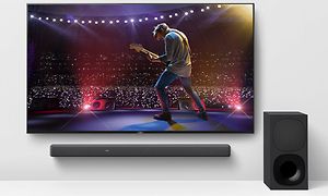 Soundbar under en TV-skärm som visar en konsert från en scen med en gitarrspelare och publik nedanför