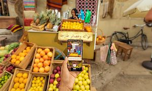 Hand som håller en Google Pixel 7 Pro med hjälp av Live Translate för att översätta en skylt till svenska på en fruktmarknad
