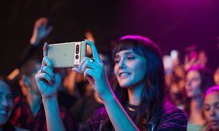 Kvinna som står på en konsert och filmar på sin Google Pixel 7 Pro