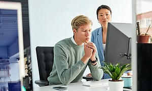 Två kollegor på ett kontor framför en PC
