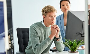 Två kollegor på ett kontor framför en PC