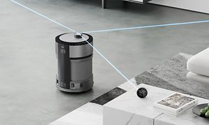 Rörlig och trådlös luftrenande robot mäter rummet på ett grått vardagsrumsgolv vid ett bord och en soffa