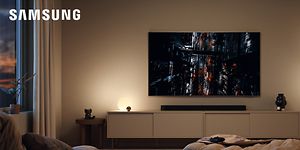 Samsung gaming-TV som visar en stad i kvällsmörker i ett vardagsrum med dämpad belysning över en soundbar och en TV-möbel