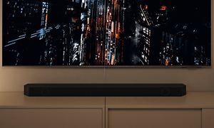 Samsung Neo QLED gaming-TV som en visar en stad i mörkret ovanifrån med en Q-Soundbar under skärmen