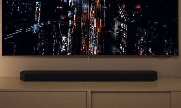 Samsung Neo QLED gaming-TV som en visar en stad i mörkret ovanifrån med en Q-Soundbar under skärmen