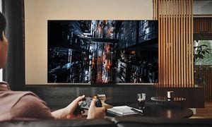 En kille i ett vardagsrum som spelar videospel på en Samsung Neo QLED gaming-TV med Low input lag