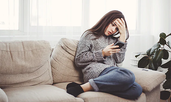 Frustrrerad och ledsen tjej ser på sin mobiltelefon