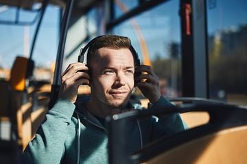 Man on a bus putting on headphones