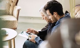 Man and old woman looking at a tablet