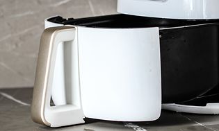 Närbild på en öppen airfryer på en svart köksbänk