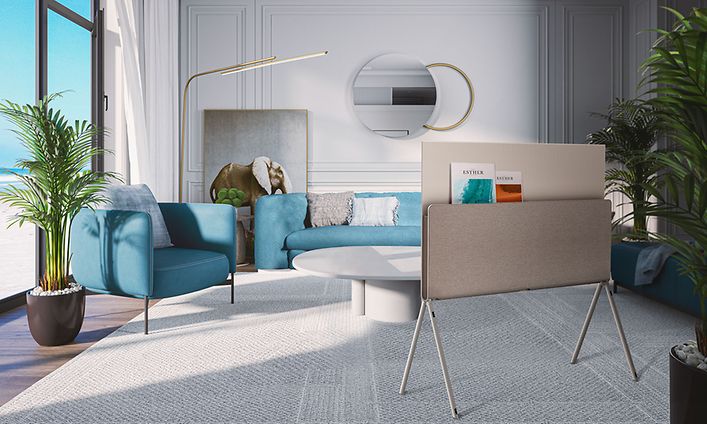 LG TV som visar sin baksida med tidningar i ett modernt vardagsrum med blå soffor, beige matta och strand utanför