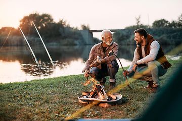 Men grilling fish by river