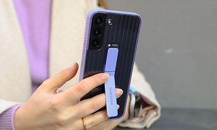 En kvinna håller i en Samsung-telefon med ett skyddande fodral med ljuslila fot