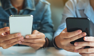 Tre personer som sitter med sina mobiltelefoner vid ett bord