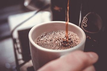 En kopp kaffe hälls upp från en kaffemaskin.