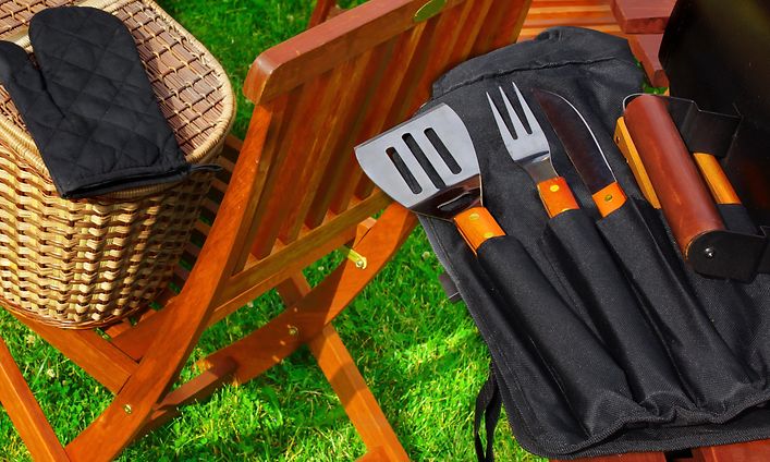Grilltillbehör och grillredskap bredvid en grill.