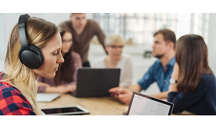 woman wearing a noise cancelling headset to focus while people are talking