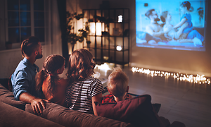 Hemmabio: Familjen tittar på en film genom en projektor på en duk.