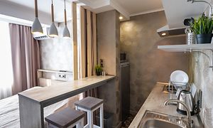 A small kitchen with a bar desk as dining table, next to a bed