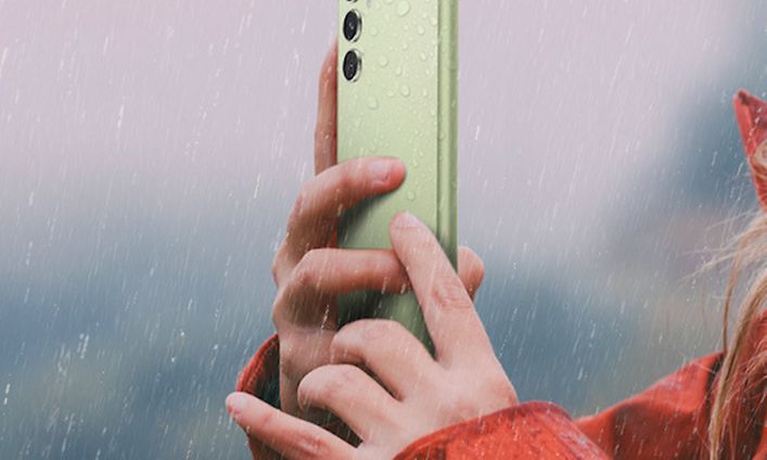 Kvinna som håller en ljusgrön Galaxy A54 5G i regn
