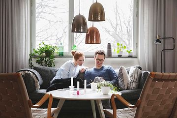 Couple sitting in sofa looking at phone