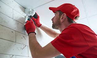 Man installing motion sensor on wall