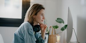 woman with headphones in front of PC