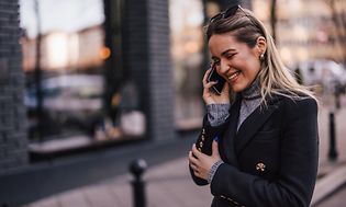 Kvinna som ler medan hon pratar i sin telefon