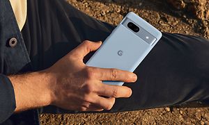 Man som håller en Google Pixel 7a på en strand