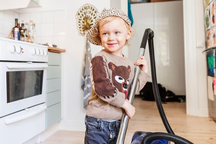 Barn med dammsugare i ett kök