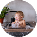 Baby sitter i en diskho och skrattar medan han leker med vatten