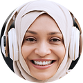 Ung kvinna som bär hörlurar över sin hijab och ler mot kameran