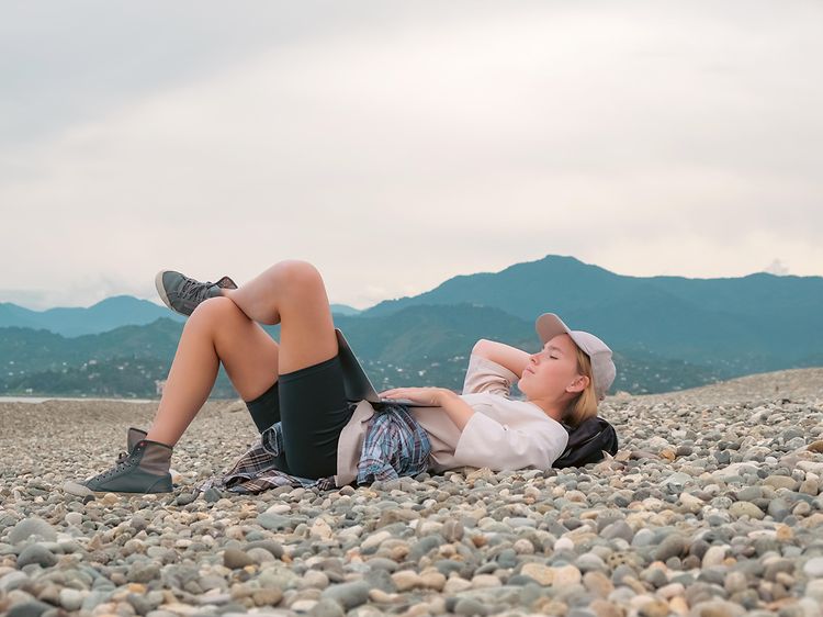 Woman lying on the beach relaxing with a laptop