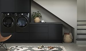 Epoq Integra Svart tvättstuga under trappa med integrerad svart tvättmaskin och torktumlare.