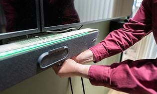 Hands adjusting speaker below TV