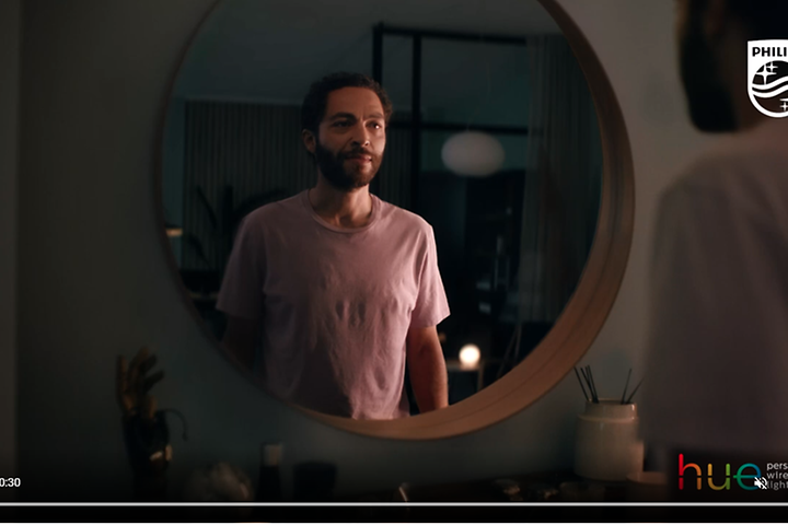 Skärmdump från video om Philips Hue med en man framför en rund spegel. 
