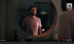Skärmdump från video om Philips Hue med en man framför en rund spegel. 
