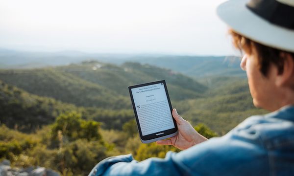 A man looking at his Pocketbook with mountains in the background