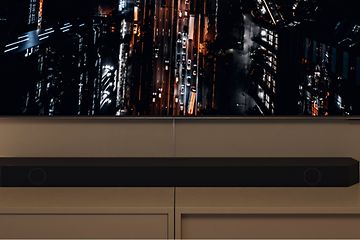 Samsung-soundbar under en TV-skärm som visar en storstad i kvällsmörker sett uppifrån