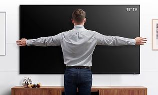 Samsung 75” TV som mäts av en man