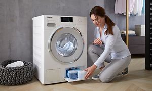 Miele washing machine with TwinDos and a woman next to it filling detergent