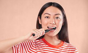 Woman brushing teeth with Philips One electrical toothbrush