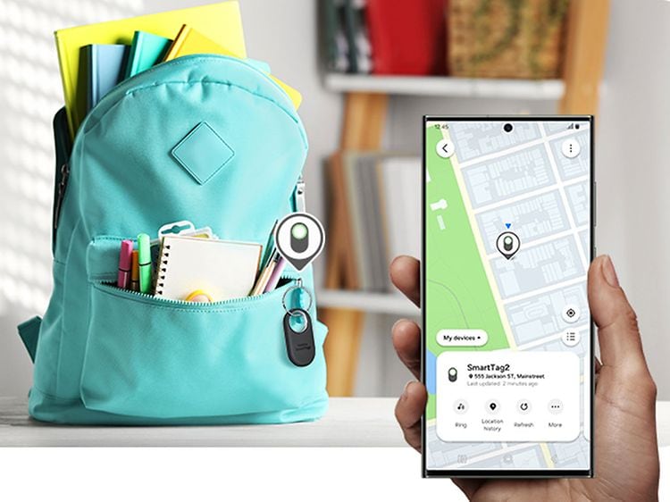 Samsung SmartTag2 Bluetooth tracker on a back bag and a hand holding smartphone with App