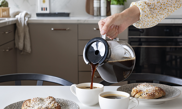 Kvinna som häller kaffe i koppar från kaffekanna