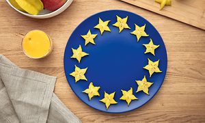 En blå tallrik på ett bord med skivor av stjärnfrukt placerade i en cirkel längs tallrikens kanter för att avbilda EU-flaggan