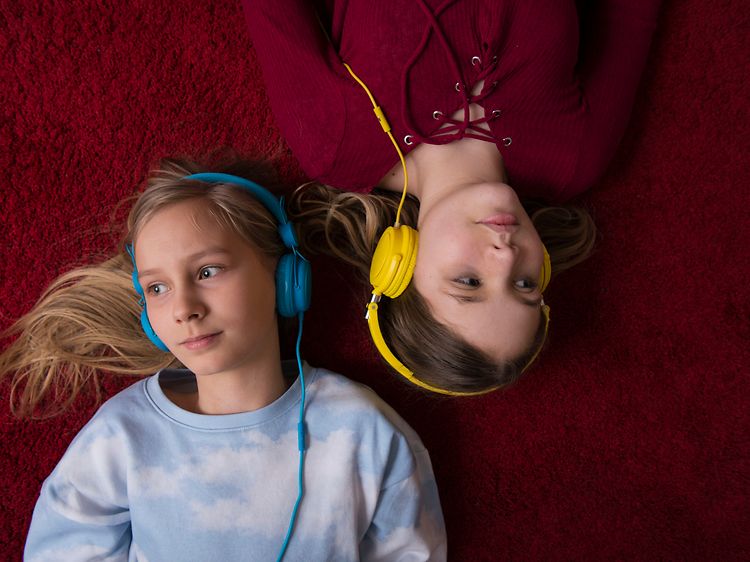 Two girls with headsets laying on floor