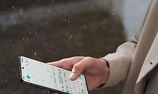 Person som smsar på sin OnePlus 12 i regnet
