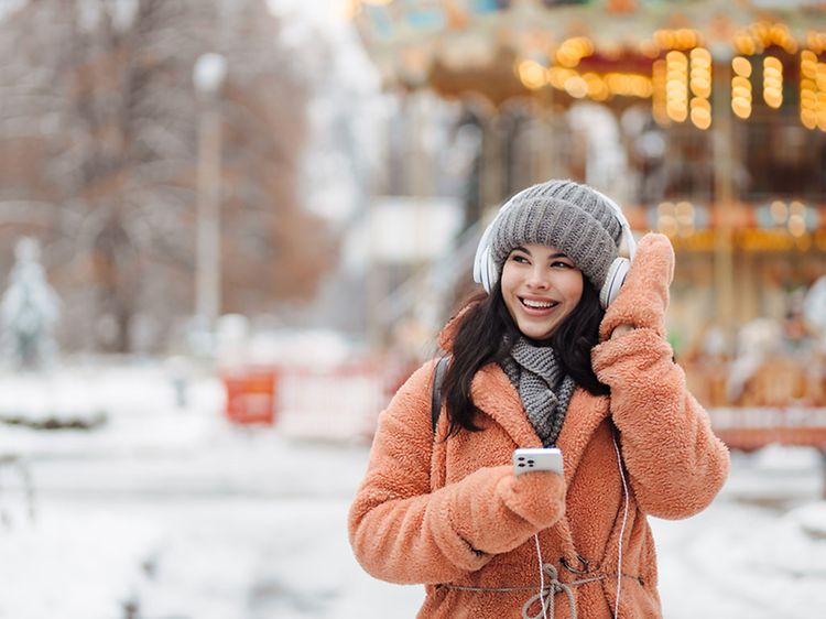 Girl with headphones and mobilephone in her hand enjoying outside on a winter day