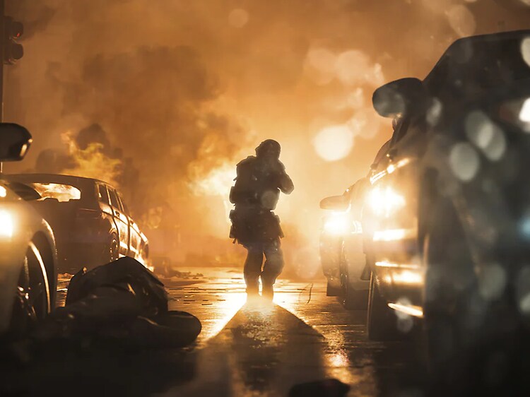 Bild från spelet Call of Duty. En man i skyddskläder med vapen går framåt på en gata bland bilar där det brinner längre fram. 