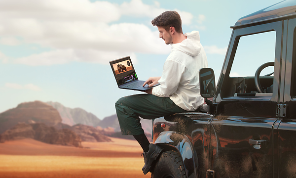 Man sitting on top of a car working with Asus ProArt P16 H7606 laptop on his lap